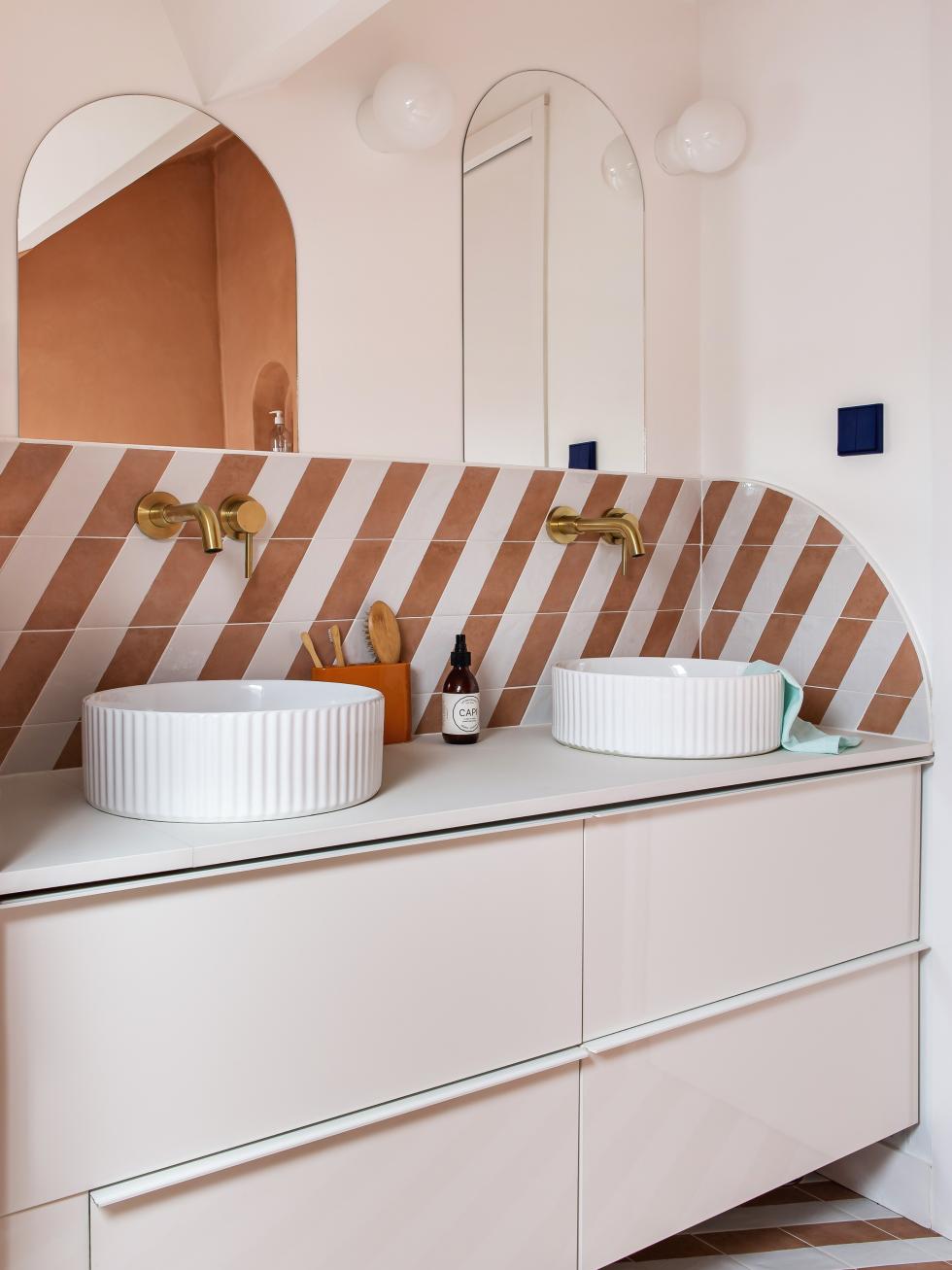 Meuble de salle de bain avec crédence en faïence bicolore et robinetterie en laiton.